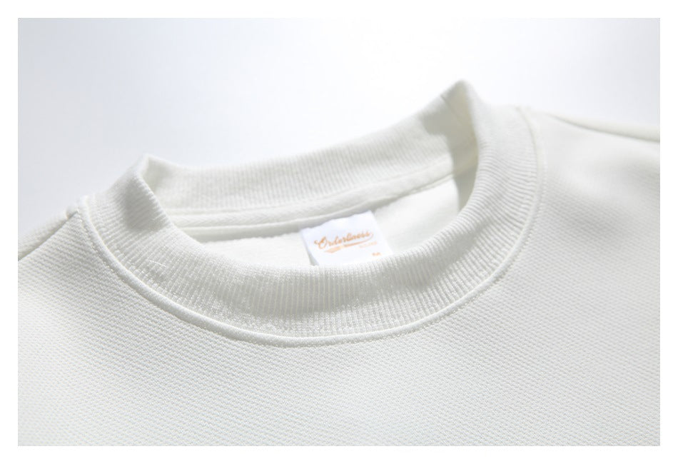 Close-up of the white sweatshirt's ribbed crew neckline and inner label.