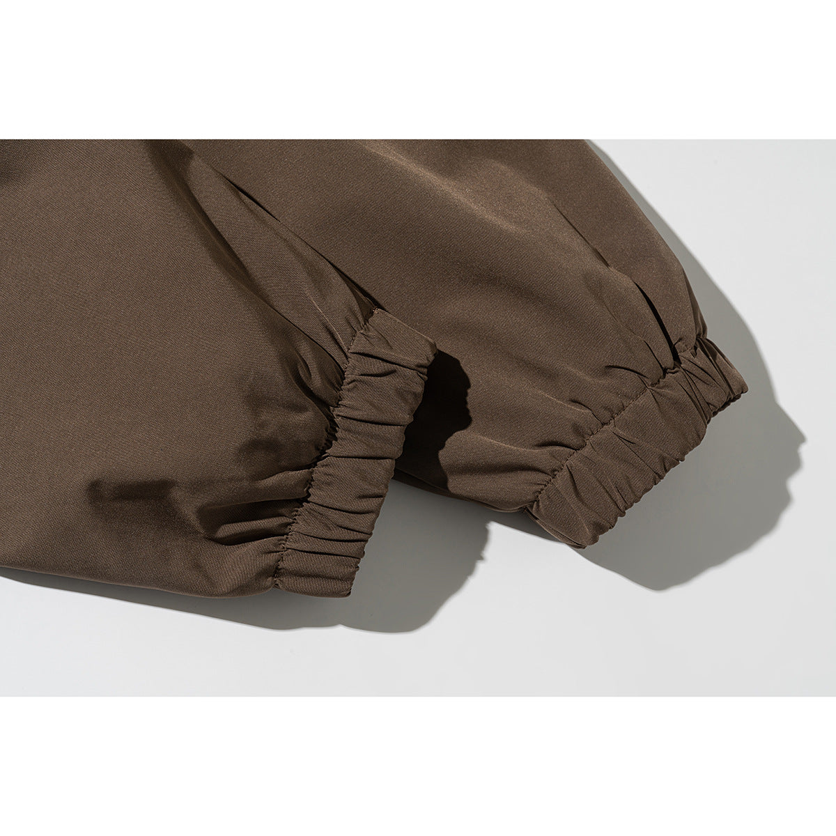 Close-up of a brown jacket's gathered elastic cuffs and sleeve seams.