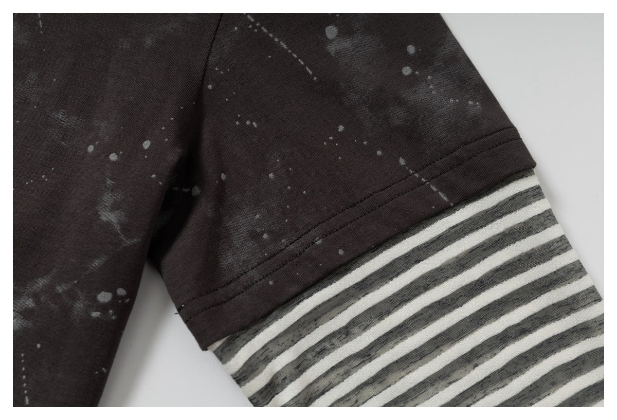 Close-up of a dark splatter-print sleeve joined to a gray-and-white striped sleeve section.