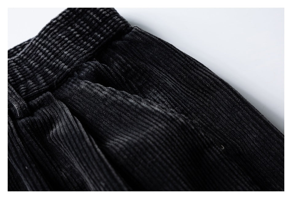 Close-up of the waistband and pocket area on black corduroy trousers.
