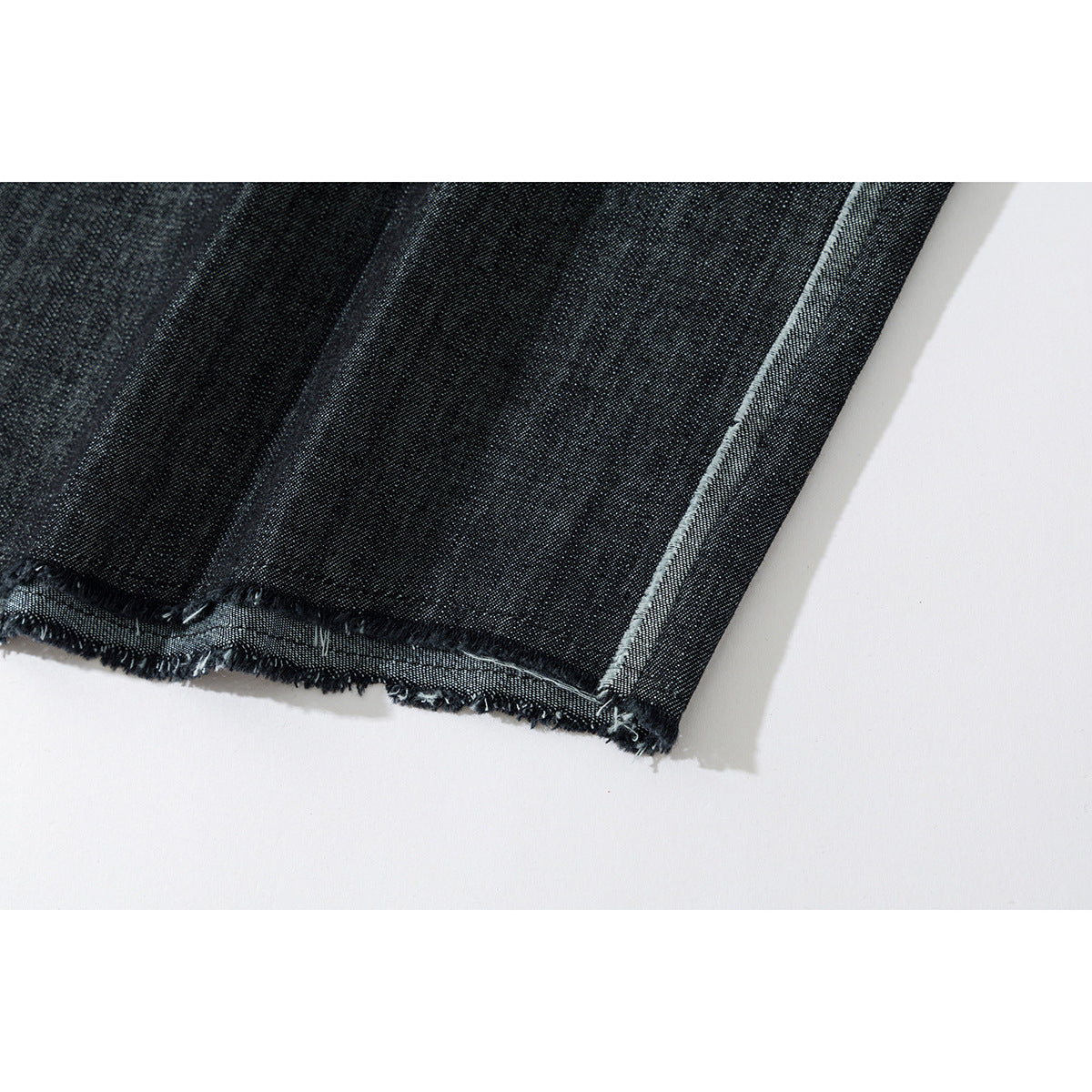 Close-up of the dark denim shirt's frayed hem and pale stitched edge.