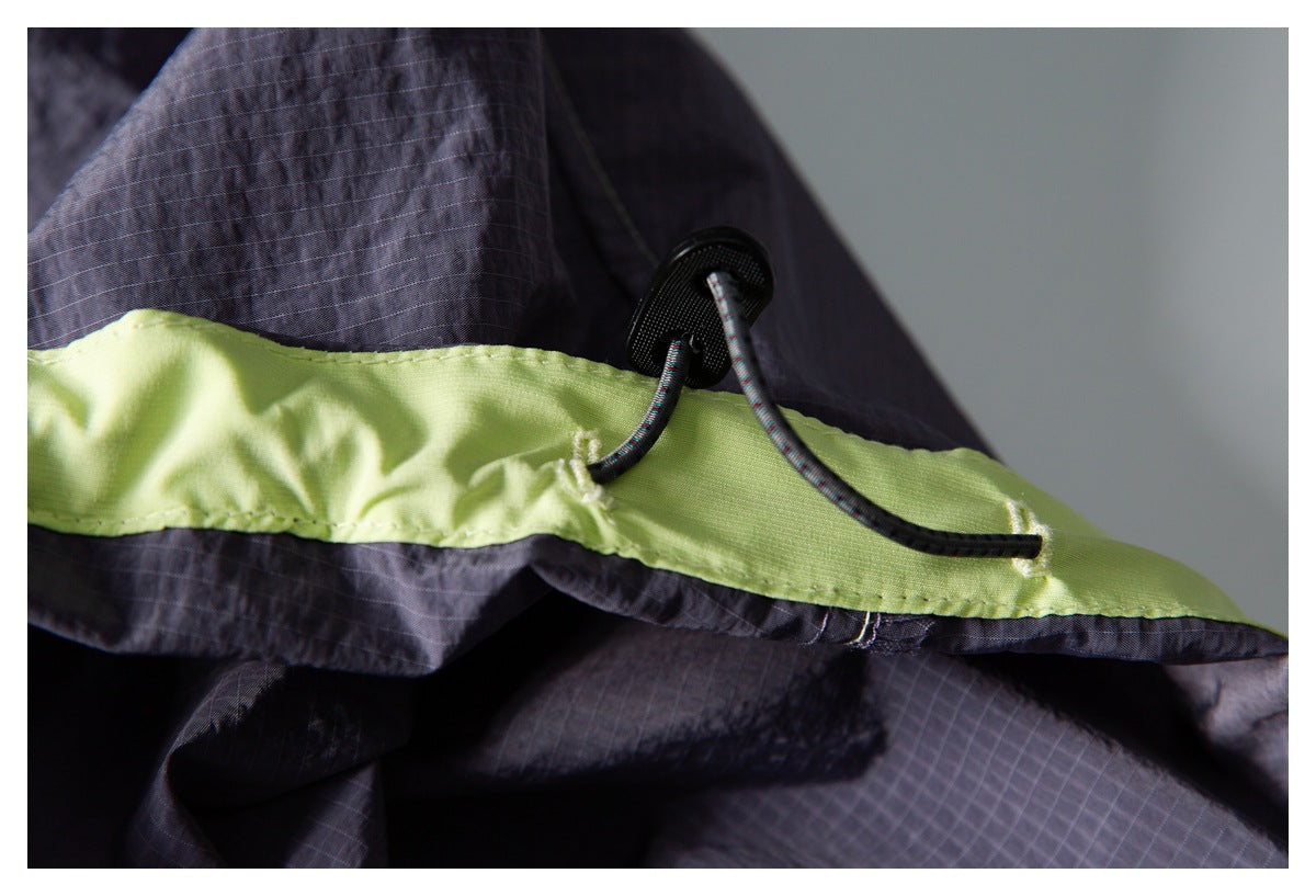 Close-up of dark gray shorts with a lime-green waistband and black drawcord toggle.