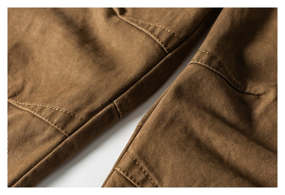 Close-up of brown trouser legs and intersecting stitched seams on a white background.