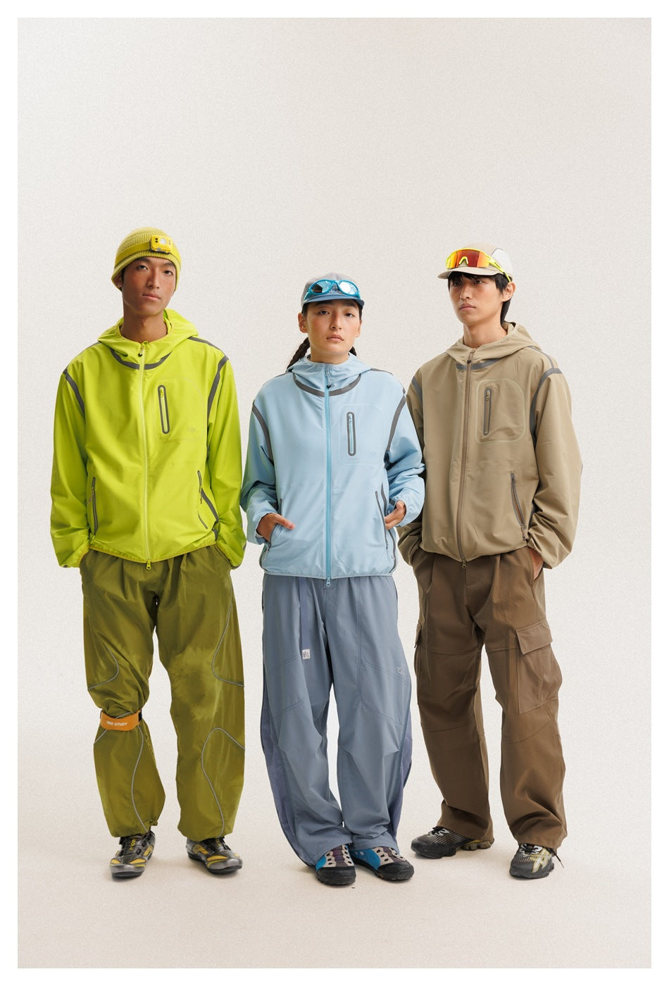 Three models show the hooded jacket in neon yellow-green, pale blue, and tan colorways from the front.