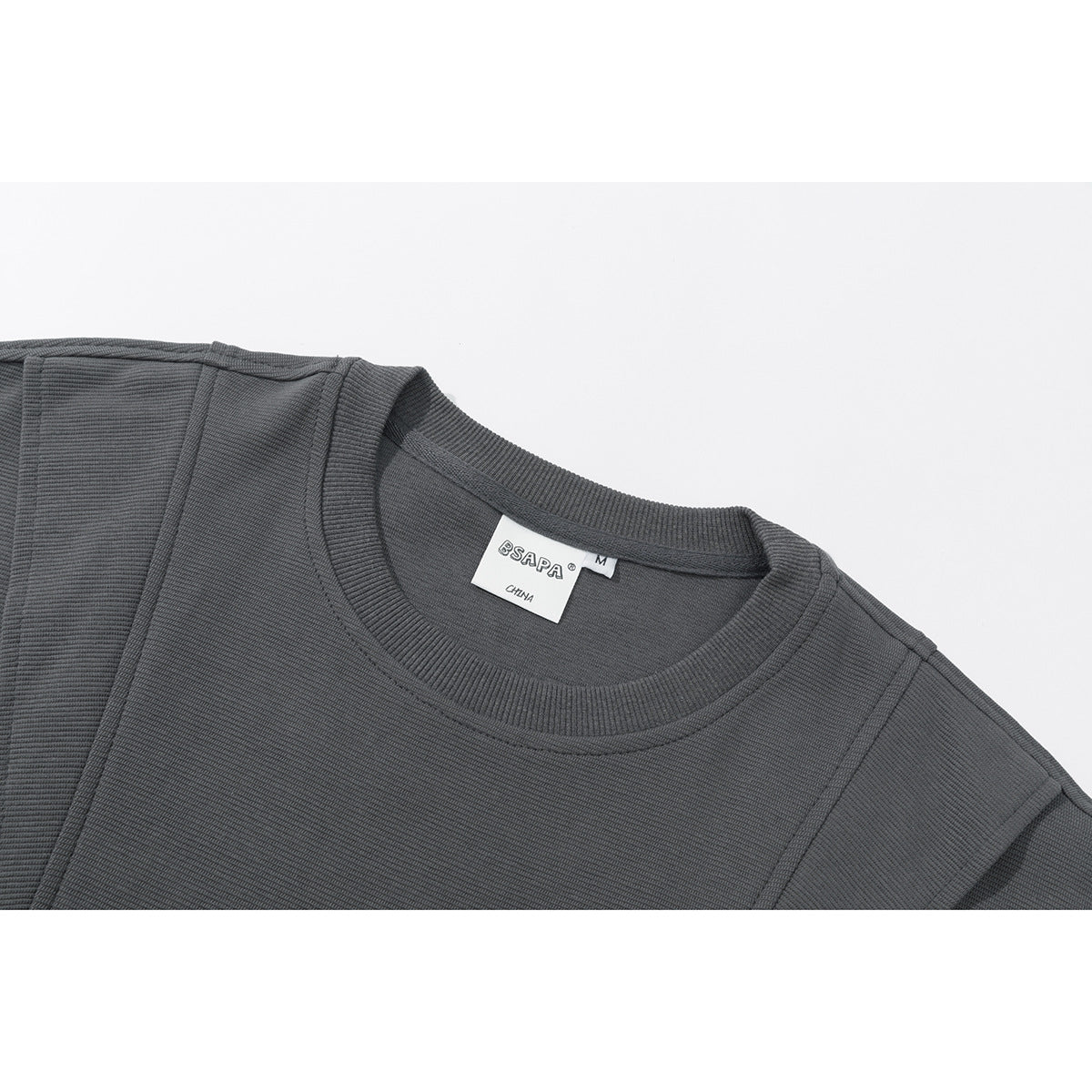 Close-up of a charcoal gray sweatshirt's ribbed crew neck, shoulder seams, and sewn neck label.