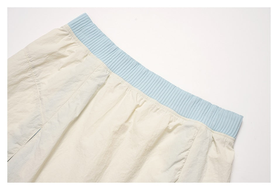 Close-up of the cream skirt's pale blue ribbed waistband and gathered fabric.