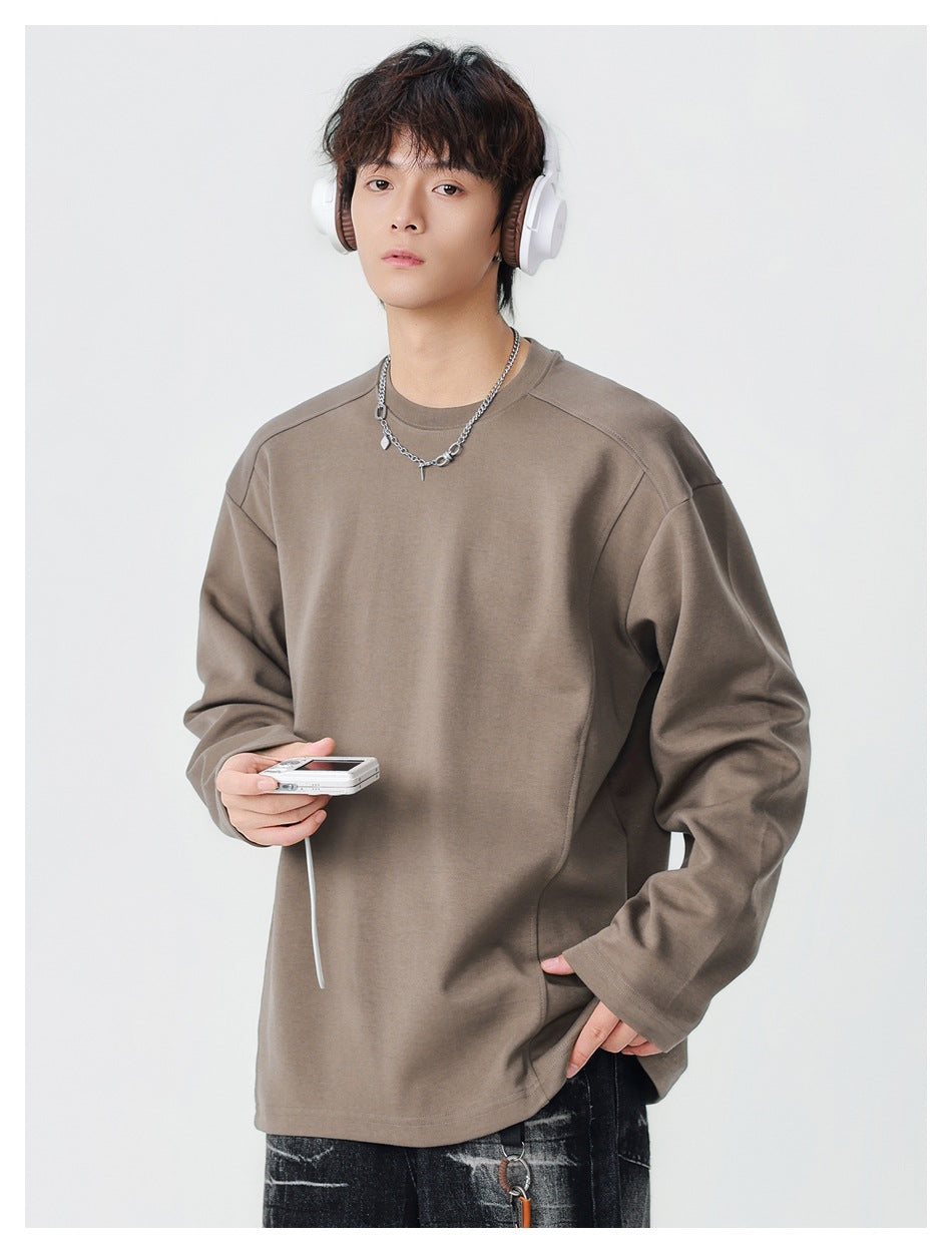 Model wearing a taupe oversized long-sleeve crewneck top with seamed shoulders.