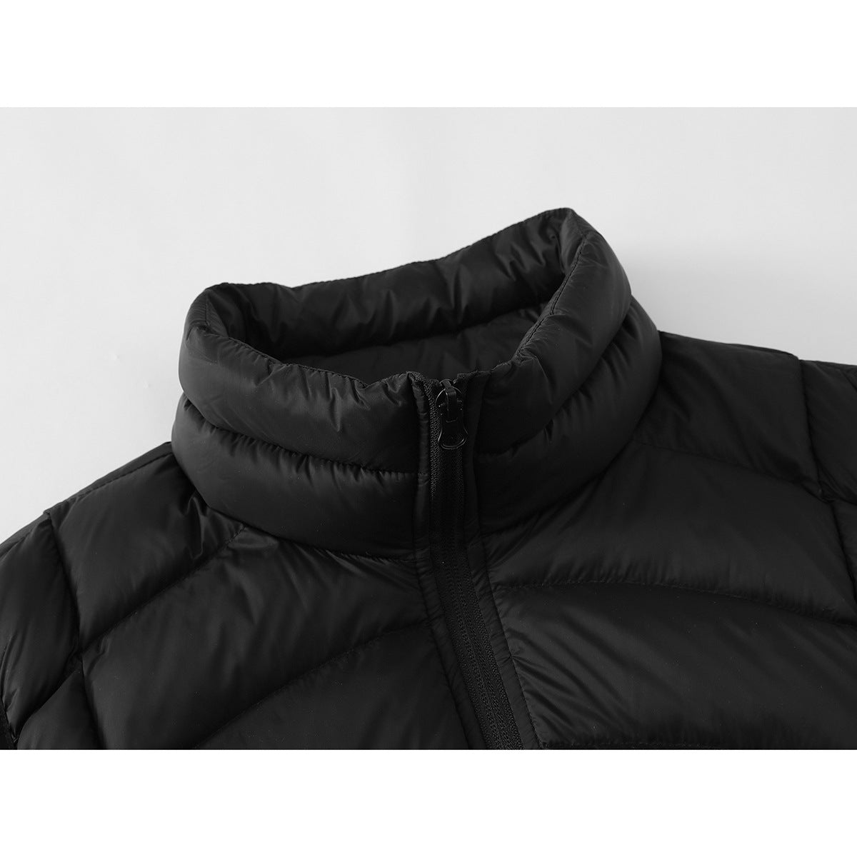 Close-up of a black quilted vest showing its padded stand collar and front zipper.