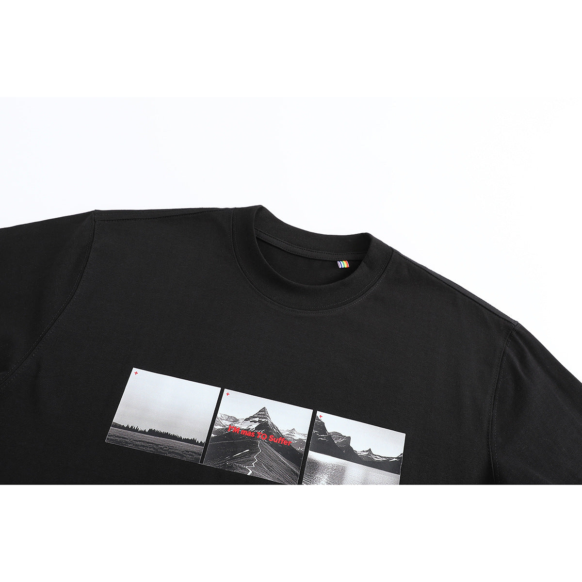 Close view of a black crew-neck T-shirt with a three-panel monochrome mountain and lake graphic and red text.