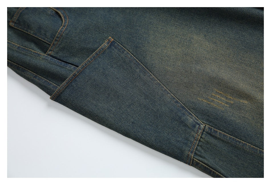 Close-up of dark blue jeans showing orange topstitching, a folded seam, and subtle worn marks.