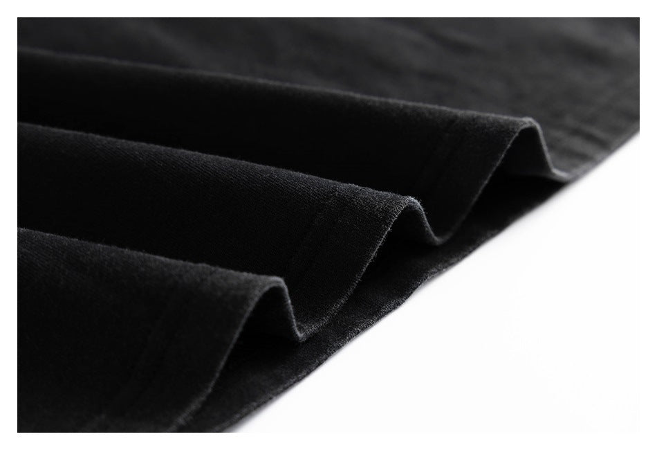 Close-up of black garment fabric folded into layers, showing a stitched edge.