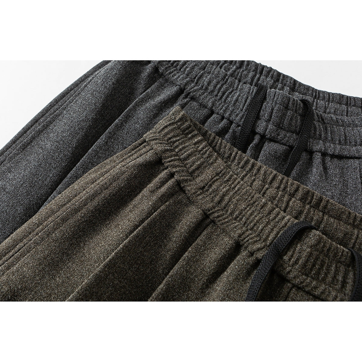 Close-up of charcoal and brown wide-leg pants showing elastic waistbands, pleats and black drawstrings.