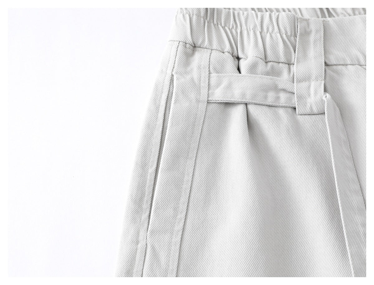 Close-up of light gray trousers showing an elastic waistband, belt loop and side seam.