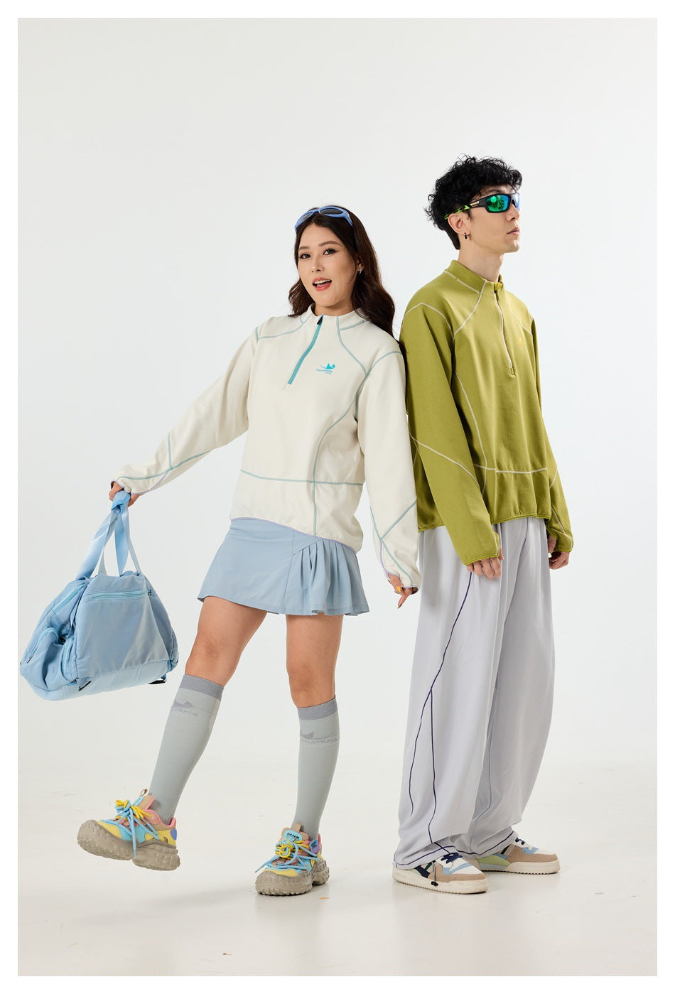 Two models pose in off-white and olive quarter-zip pullovers with contrasting seam details.