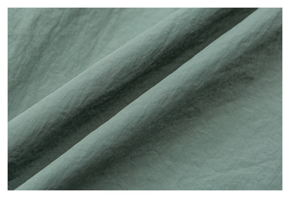 Macro view of the fine, slightly crinkled texture of sage green fabric.