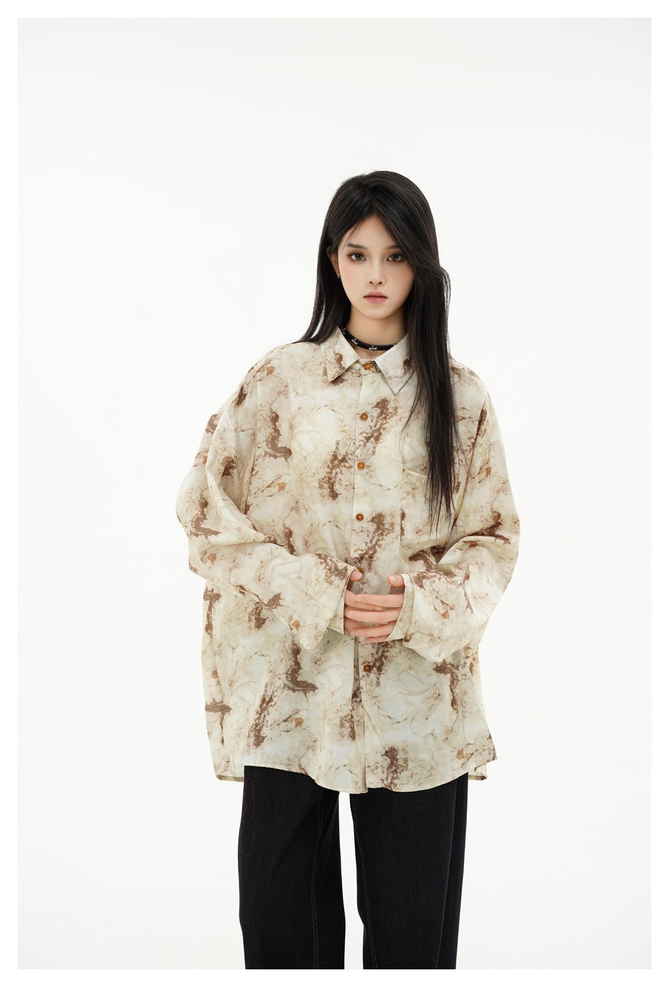 Closer view of a model wearing an oversized cream and brown abstract-print button-up shirt with a pointed collar and chest