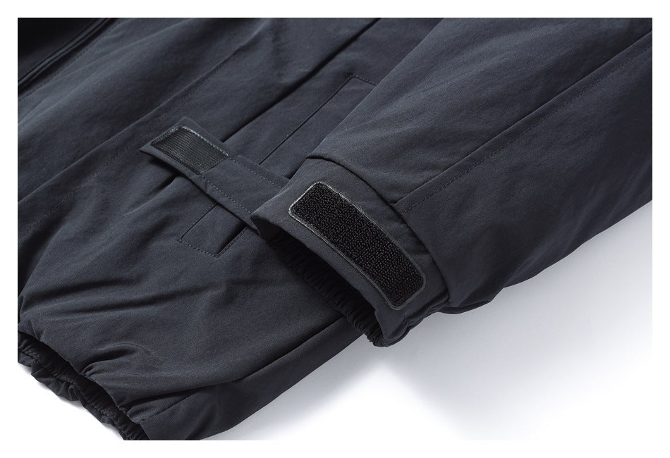 Close-up of a dark trouser cuff with the adjustable hook-and-loop tab unfastened.