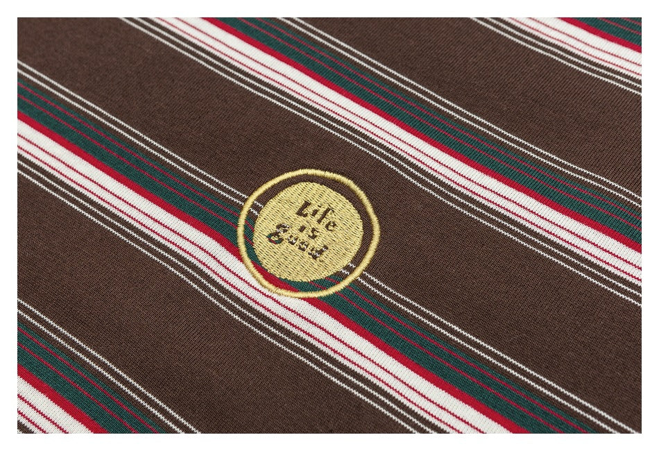 Close-up of a small circular embroidered emblem on brown knit fabric with red, green, and white stripes.