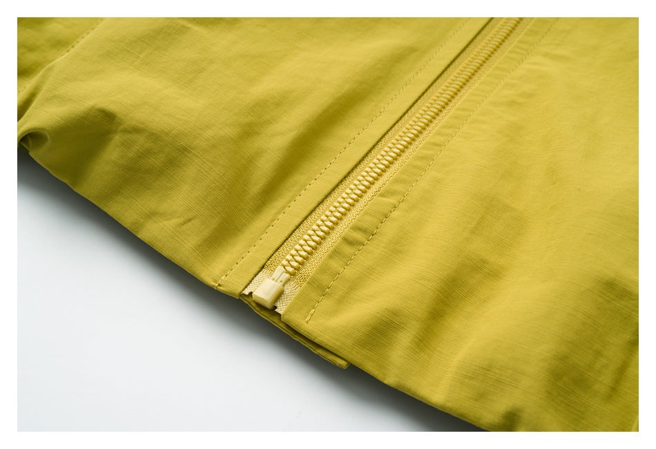 Close-up of the yellow-green garment's main zipper, zipper pull, and stitched seams.