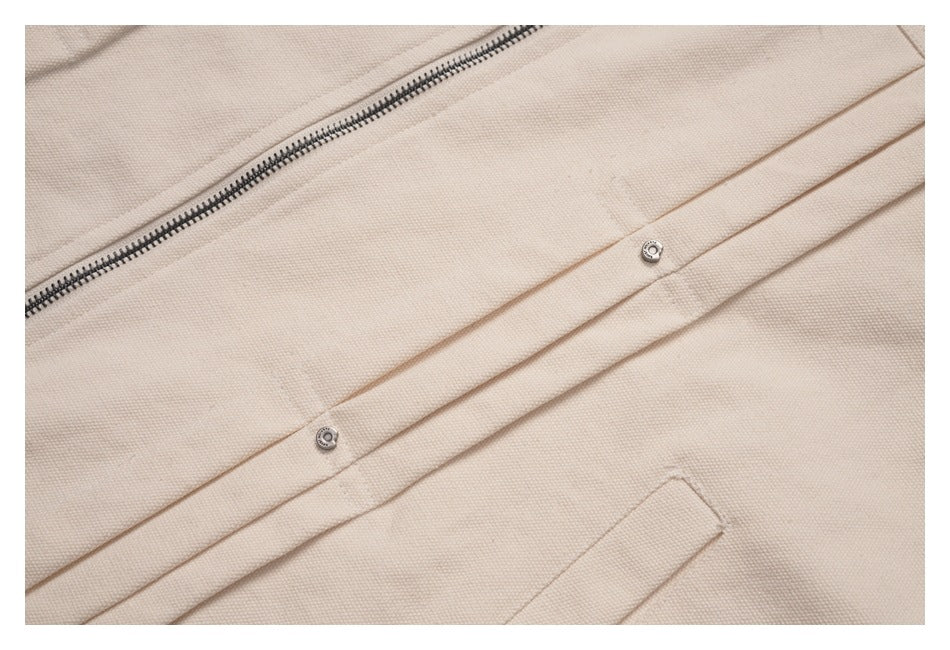 Close-up of beige jacket fabric, a metal zipper, and a snap-fastened front placket.
