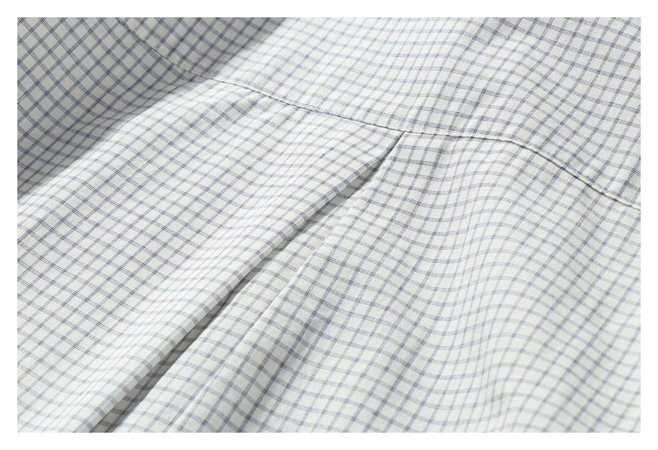 Close-up of a white shirt's blue-gray check pattern and curved seam.