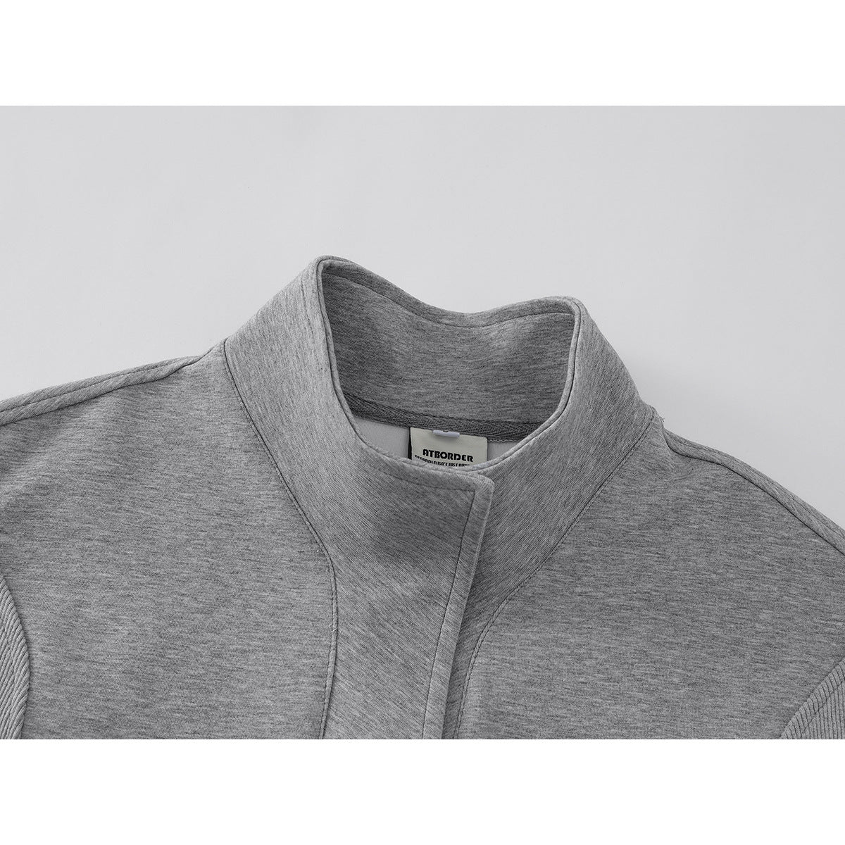 Close-up of a gray pullover's stand collar and overlapping front placket, with a sewn neck label.