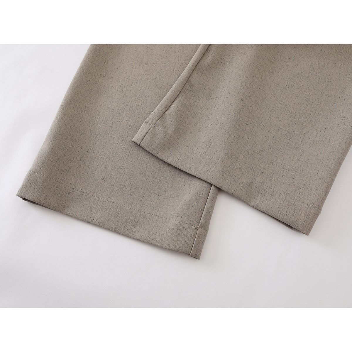 Close-up of the straight hems on taupe wide-leg trousers.