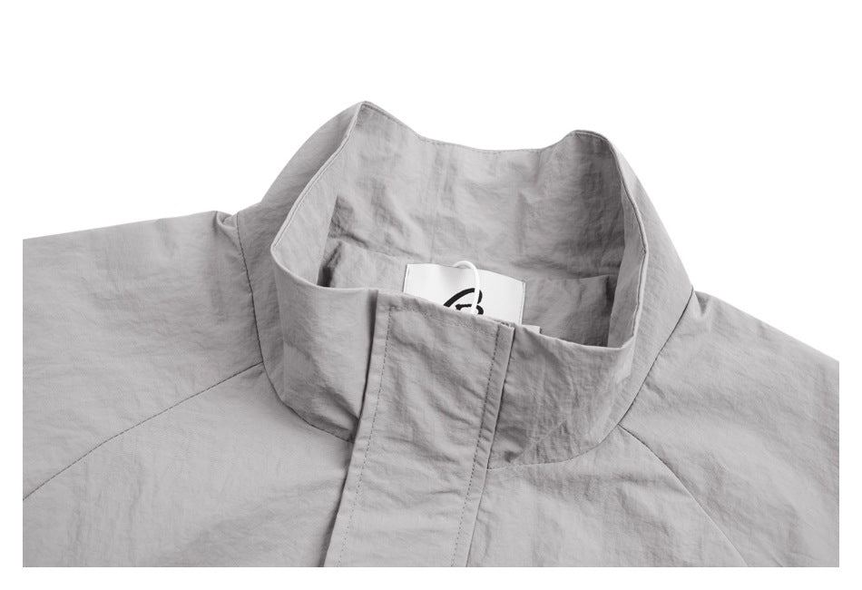 Close-up of a light gray jacket’s tall collar and front placket, with a partially visible inner neck tag.