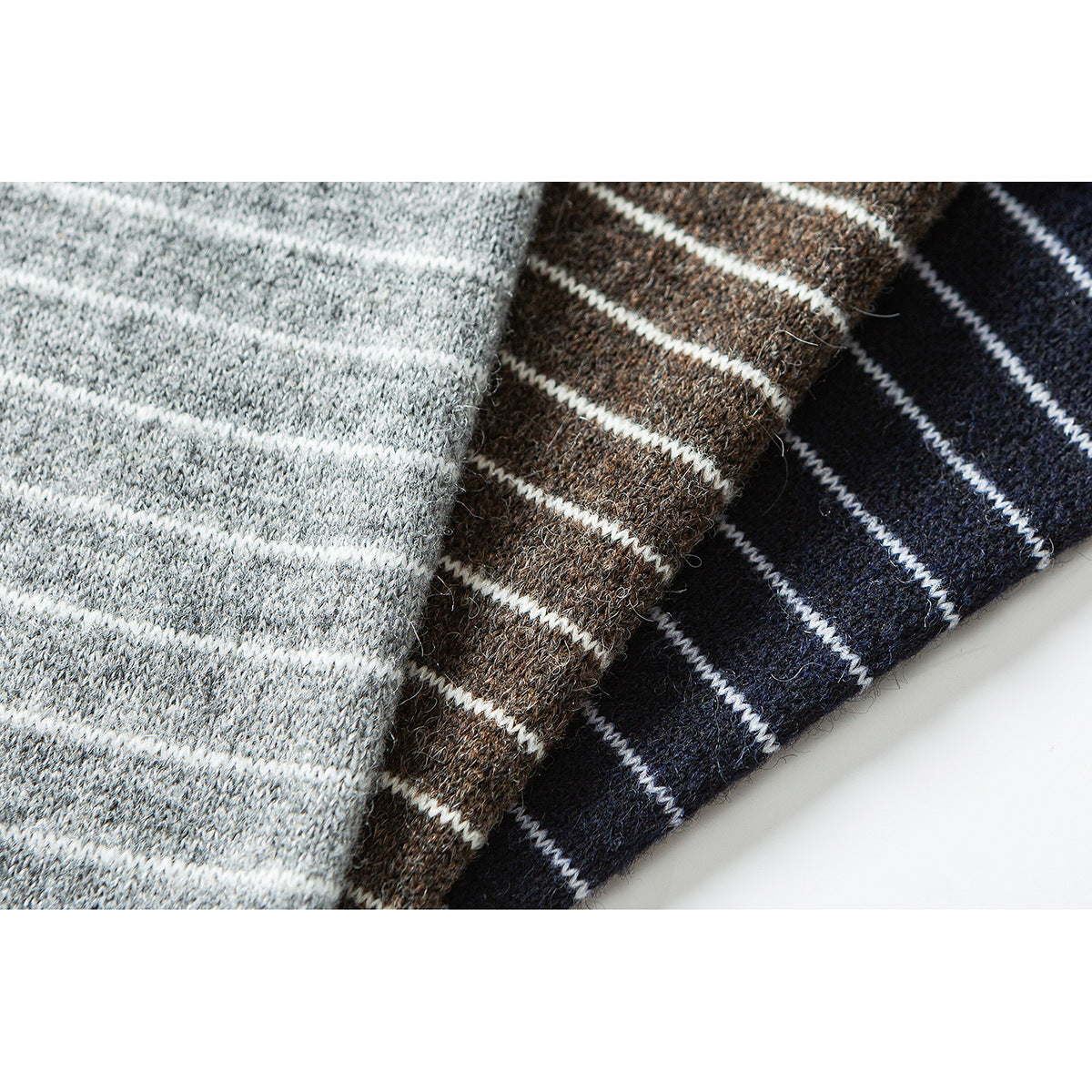 Close-up of three striped knit fabrics in light gray, brown and navy colorways.