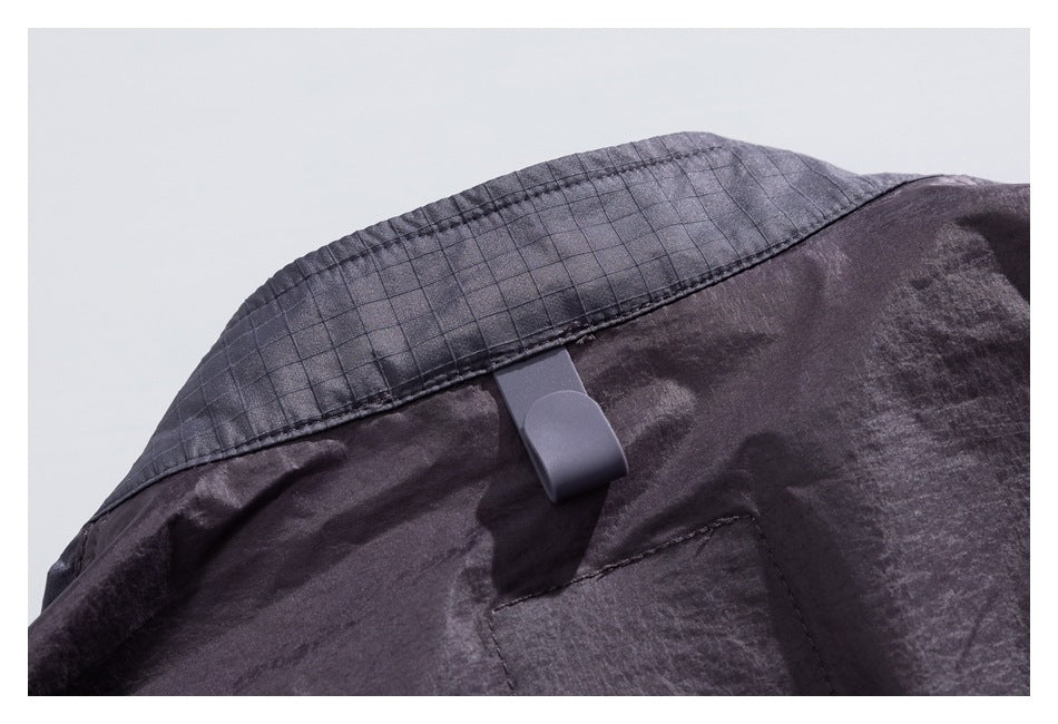 Close-up of the back yoke of a charcoal jacket, showing a gray hanging loop and stitched panel.