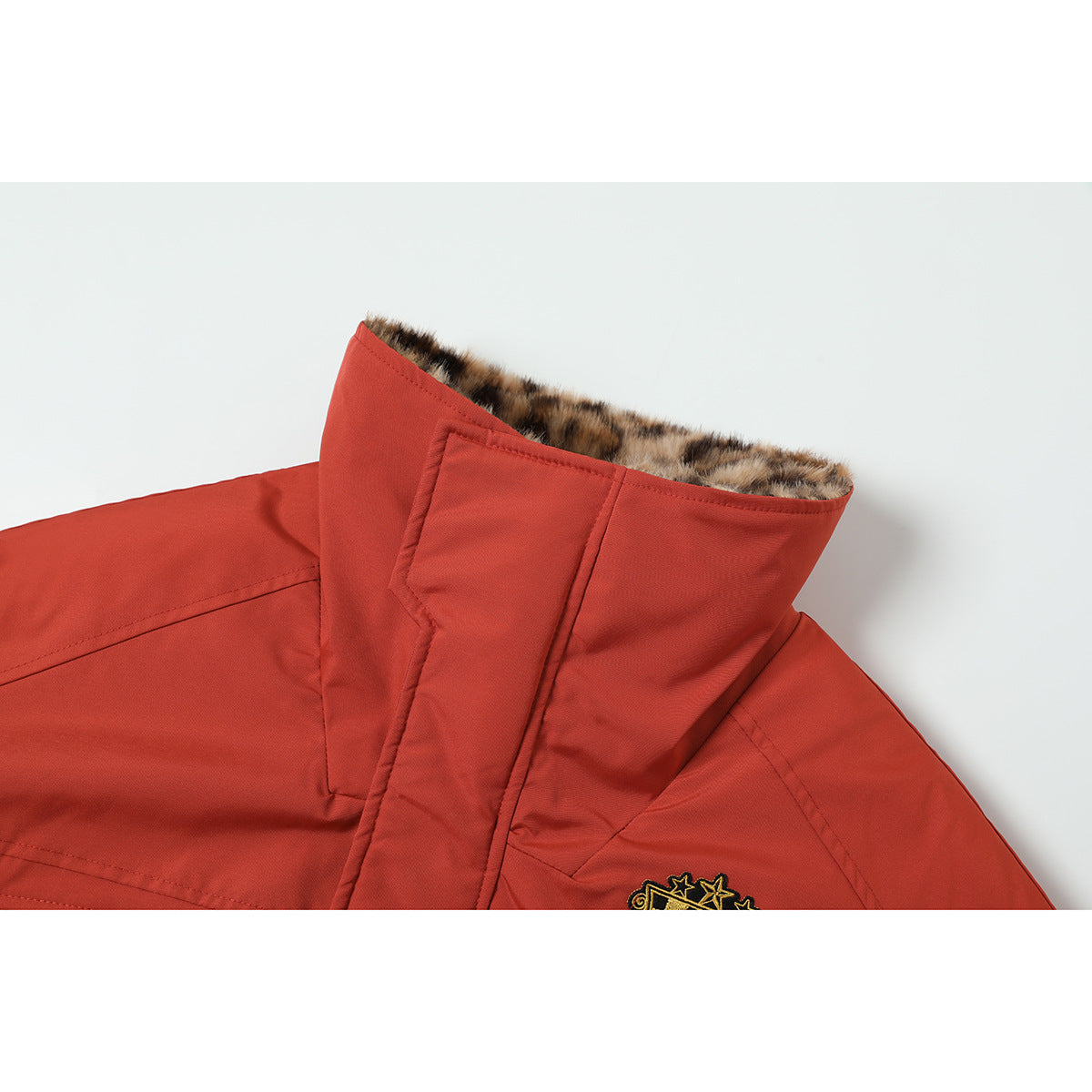 Close-up of a rust-red jacket's raised collar with leopard-print lining and a partially visible embroidered chest patch.