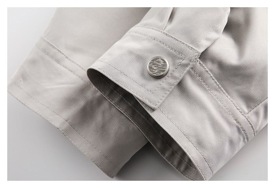 Close-up of a light gray cuff tab fastened with a round metal button.