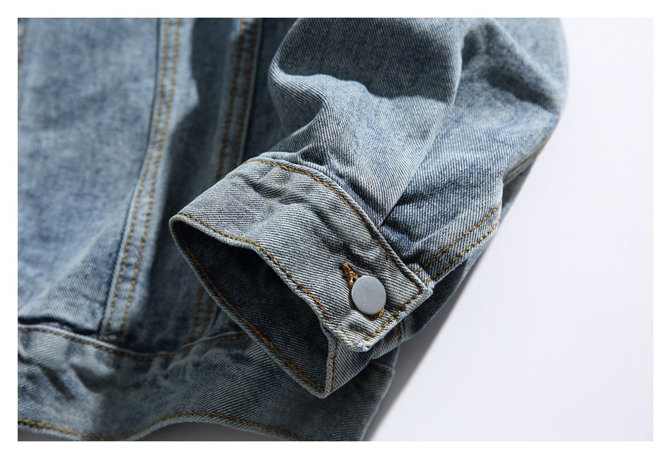 Close-up of a denim jacket sleeve cuff with a silver snap button.