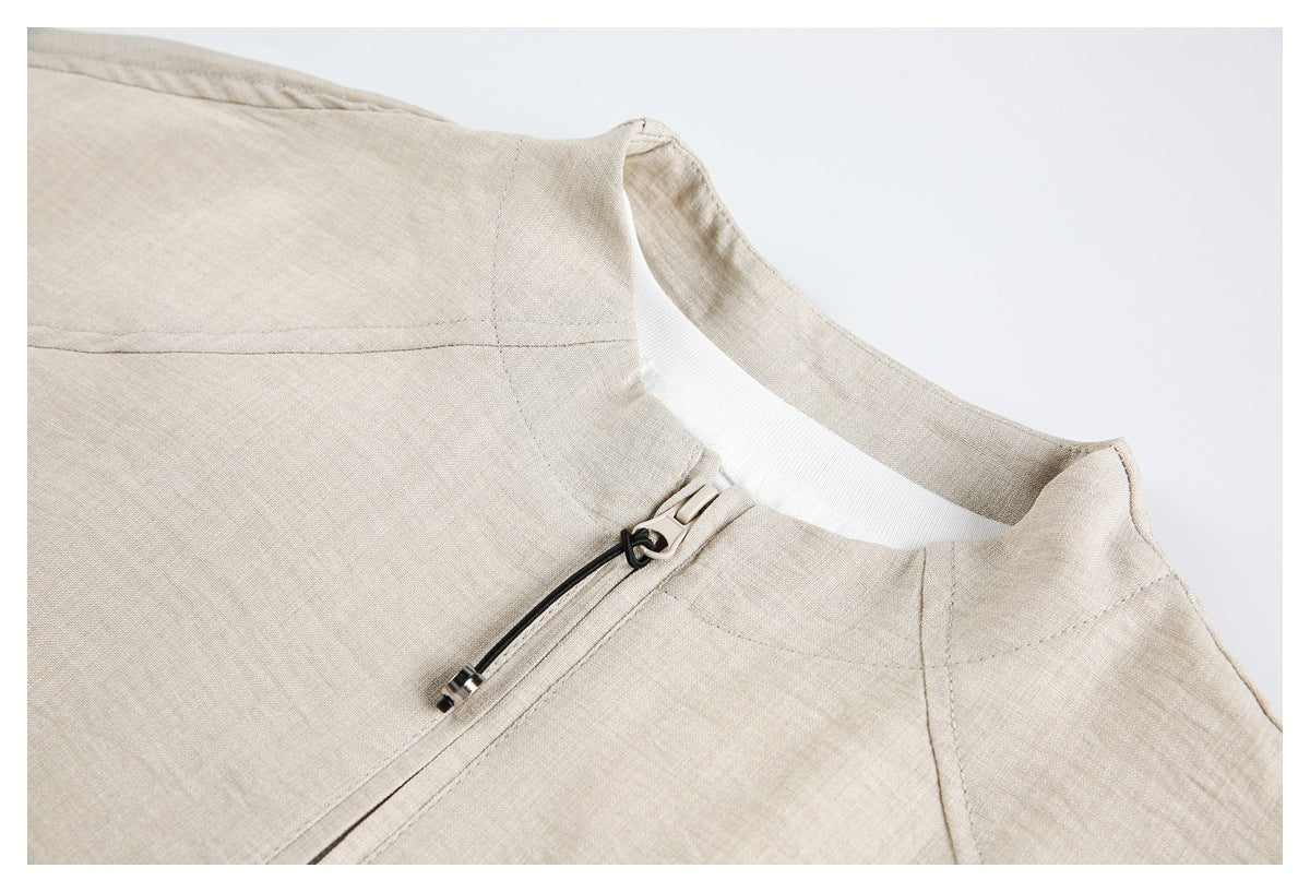 Close-up of an ivory jacket's stand collar and upper-front zipper with a black cord pull.