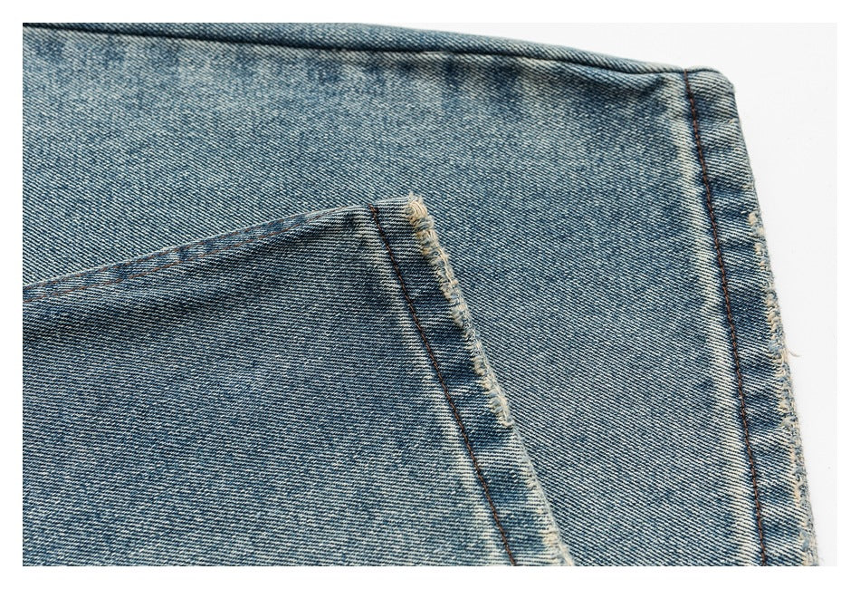 Close-up of blue denim with a stitched pocket edge and a frayed seam.