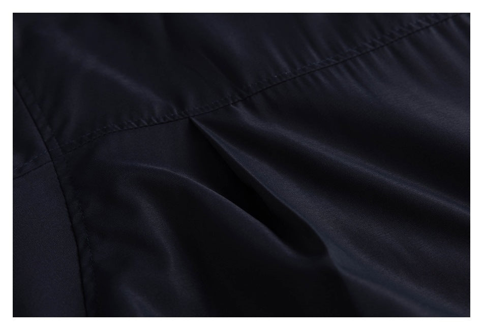 Close-up of dark navy jacket fabric showing a stitched seam and folded pleat.