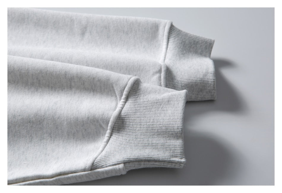 Close-up of two light gray sweatshirt sleeves with ribbed cuffs.