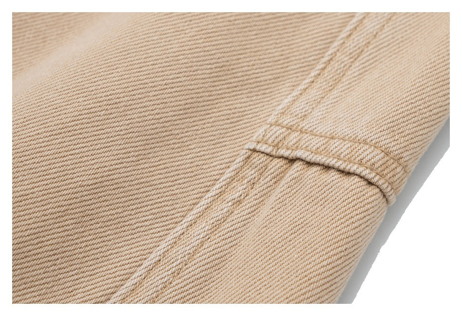 Close-up of beige twill trousers showing a stitched seam and fabric texture.