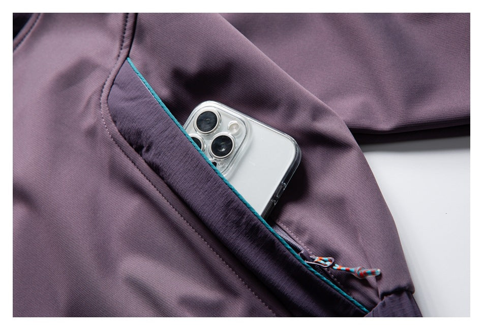 Close-up of a plum jacket sleeve pocket holding a smartphone, with teal piping and a colorful zipper pull.