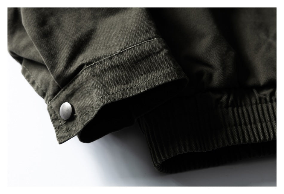Close-up of a dark olive jacket's snap-button cuff beside its gathered elastic hem.