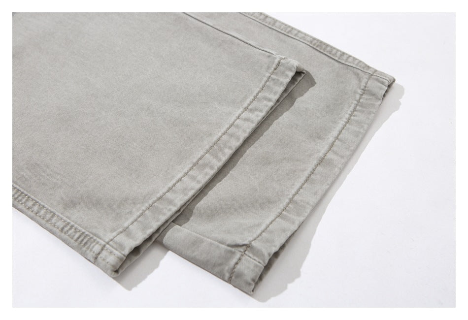 Close-up of the light gray-beige trouser legs showing stitched hems and folded cuffs.