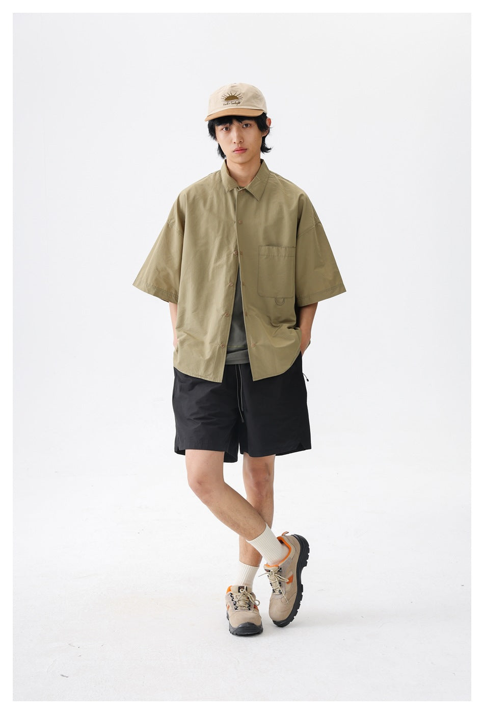 Front view of a model wearing an oversized olive short-sleeve button-up shirt with a single chest pocket.
