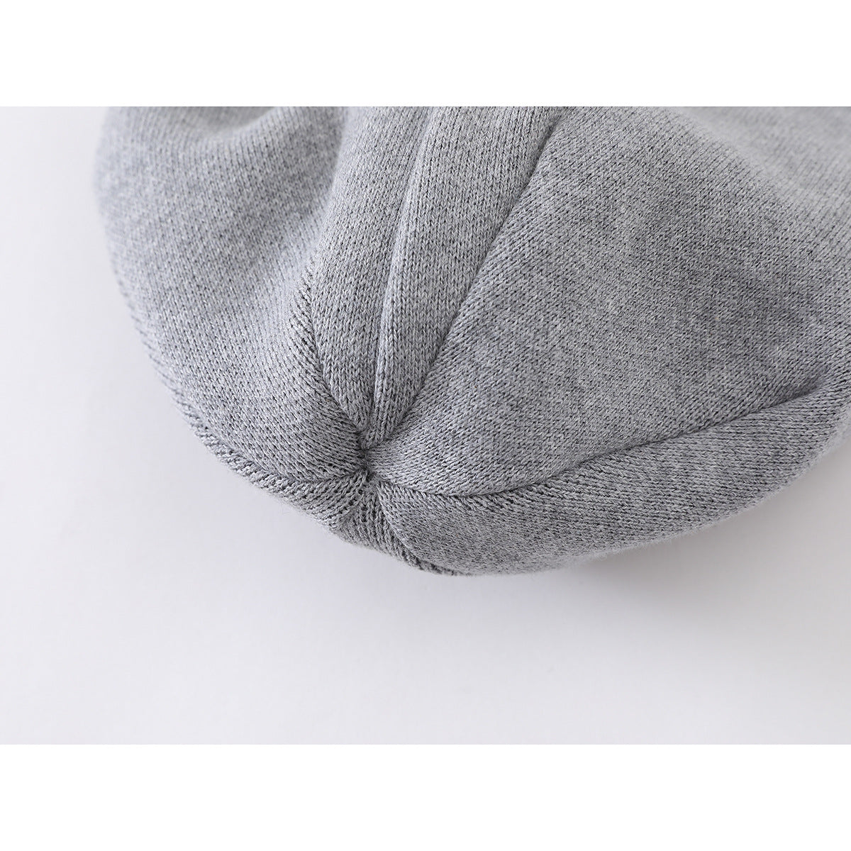 Close-up of the gray knit beanie's crown seam and gathered panels.