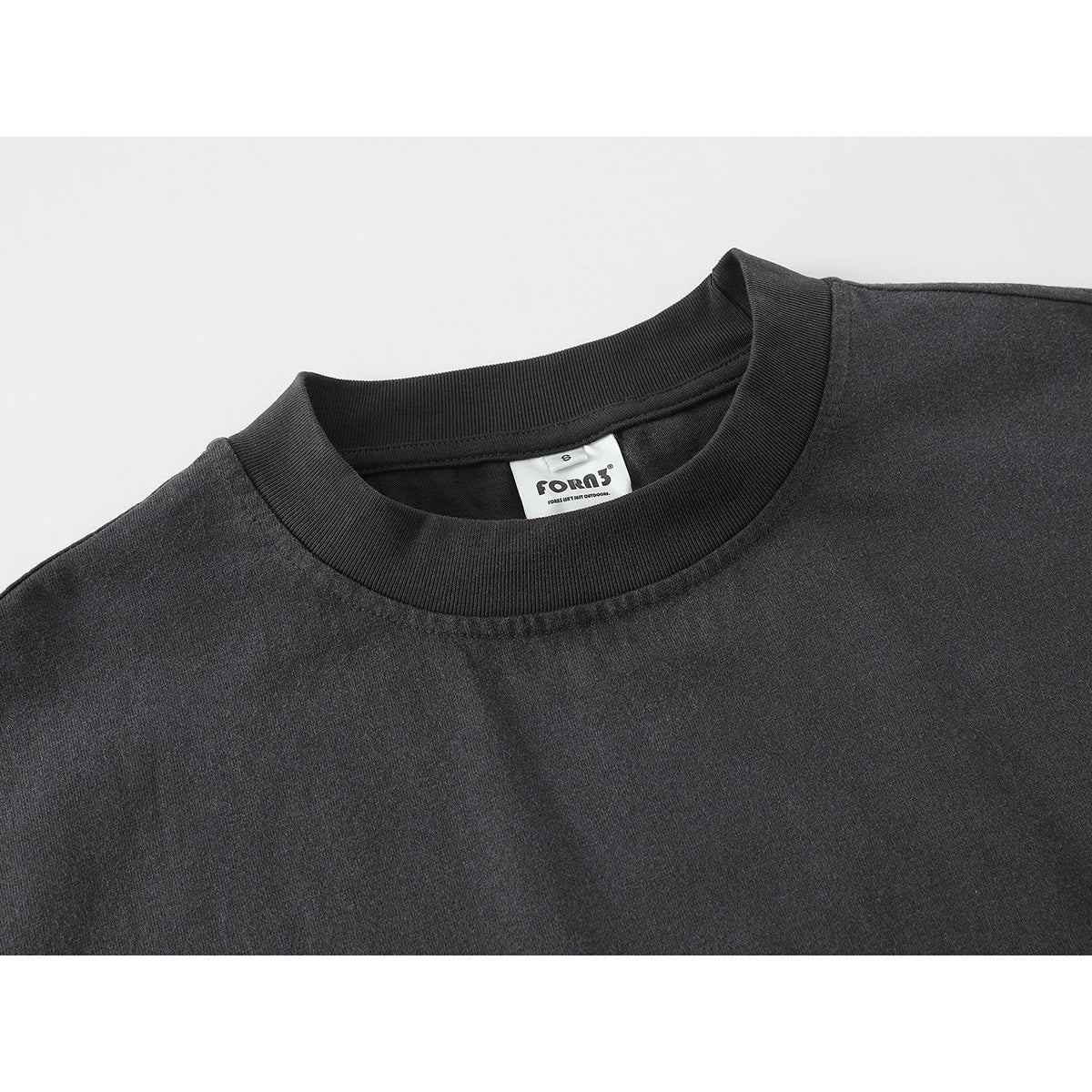 Close-up of a charcoal long-sleeve shirt's dark ribbed crew neck and inner brand label.