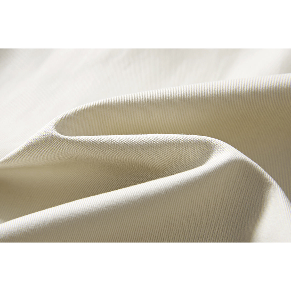 Macro view of the fine woven texture and folded drape of cream-colored fabric.