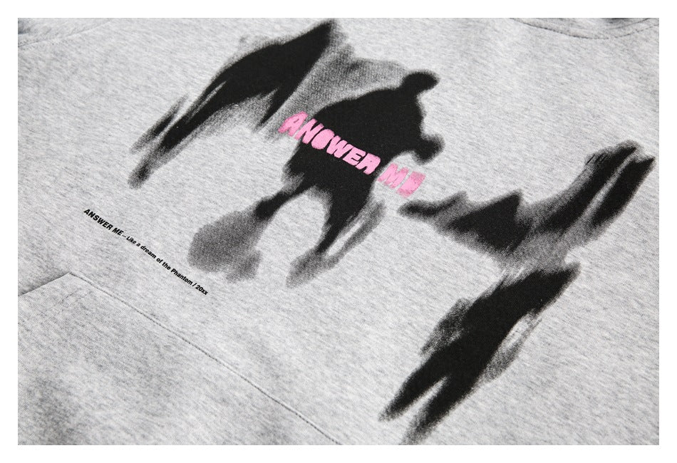 Close-up of the gray hoodie’s black brushstroke and pink chest print above the kangaroo pocket.