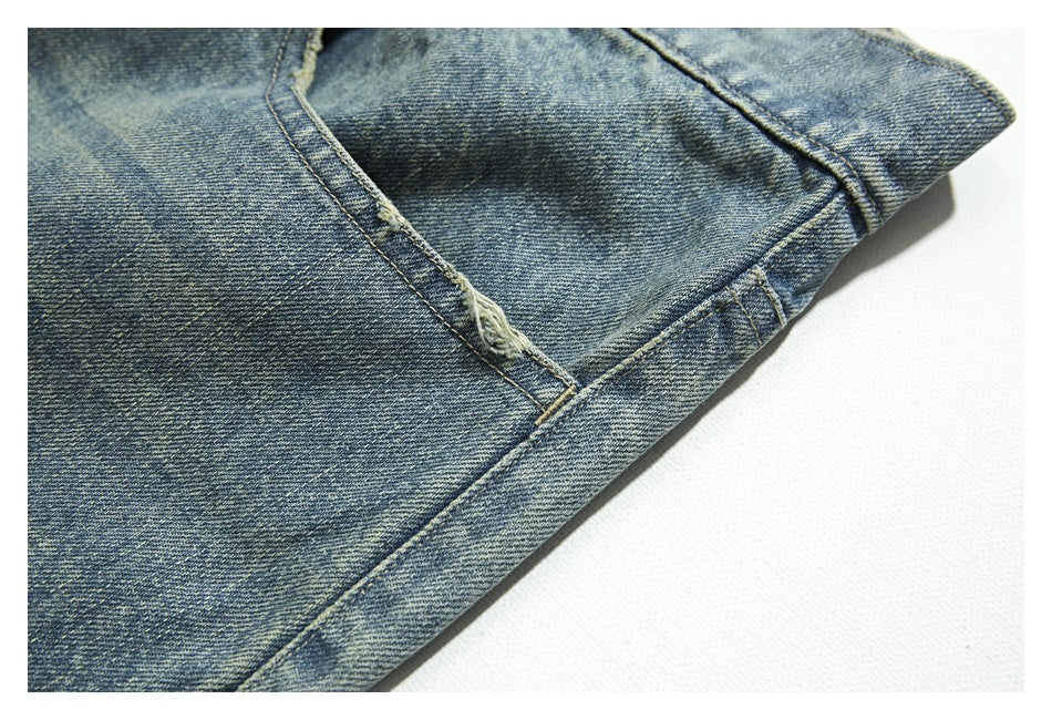 Close-up of faded blue denim with a frayed seam and pocket corner.