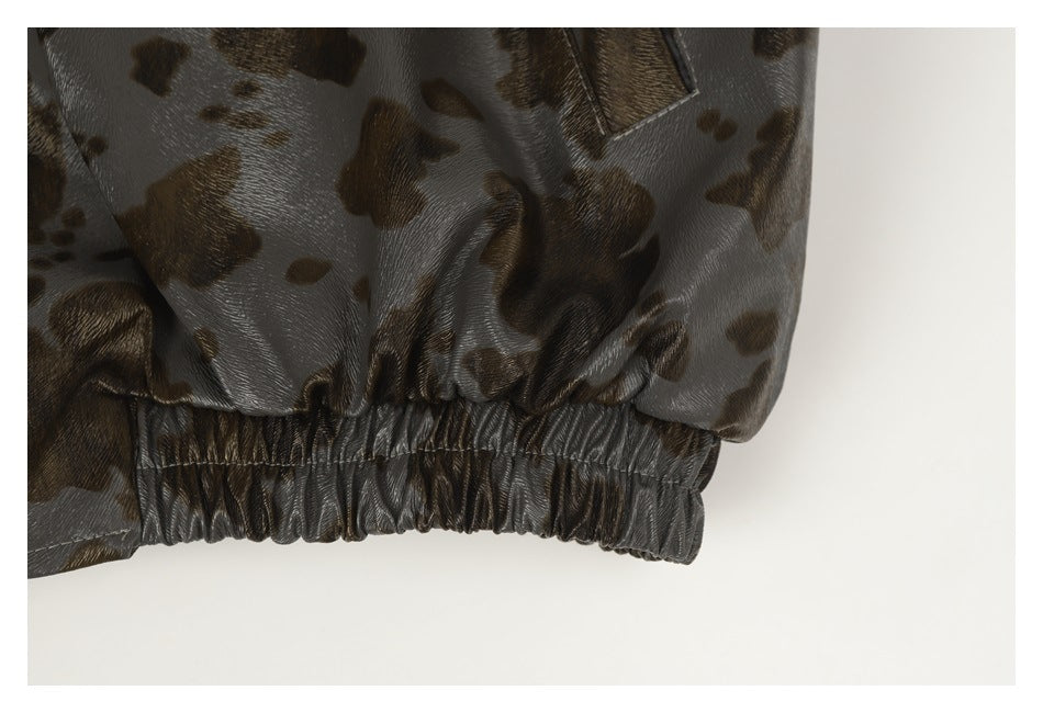 Close-up of the gathered elastic hem on glossy gray-brown spotted garment fabric.