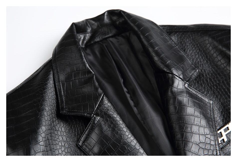 Close-up of the black jacket's crocodile-textured lapels, smooth dark lining, and a partially visible metal emblem.