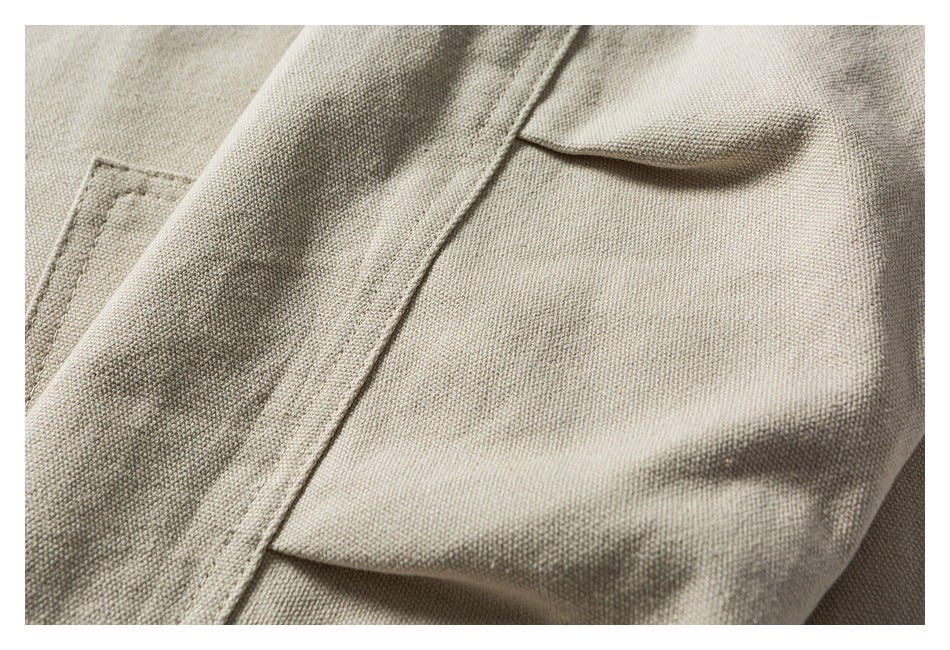 Close-up of beige woven garment fabric showing a seam and flap pocket.